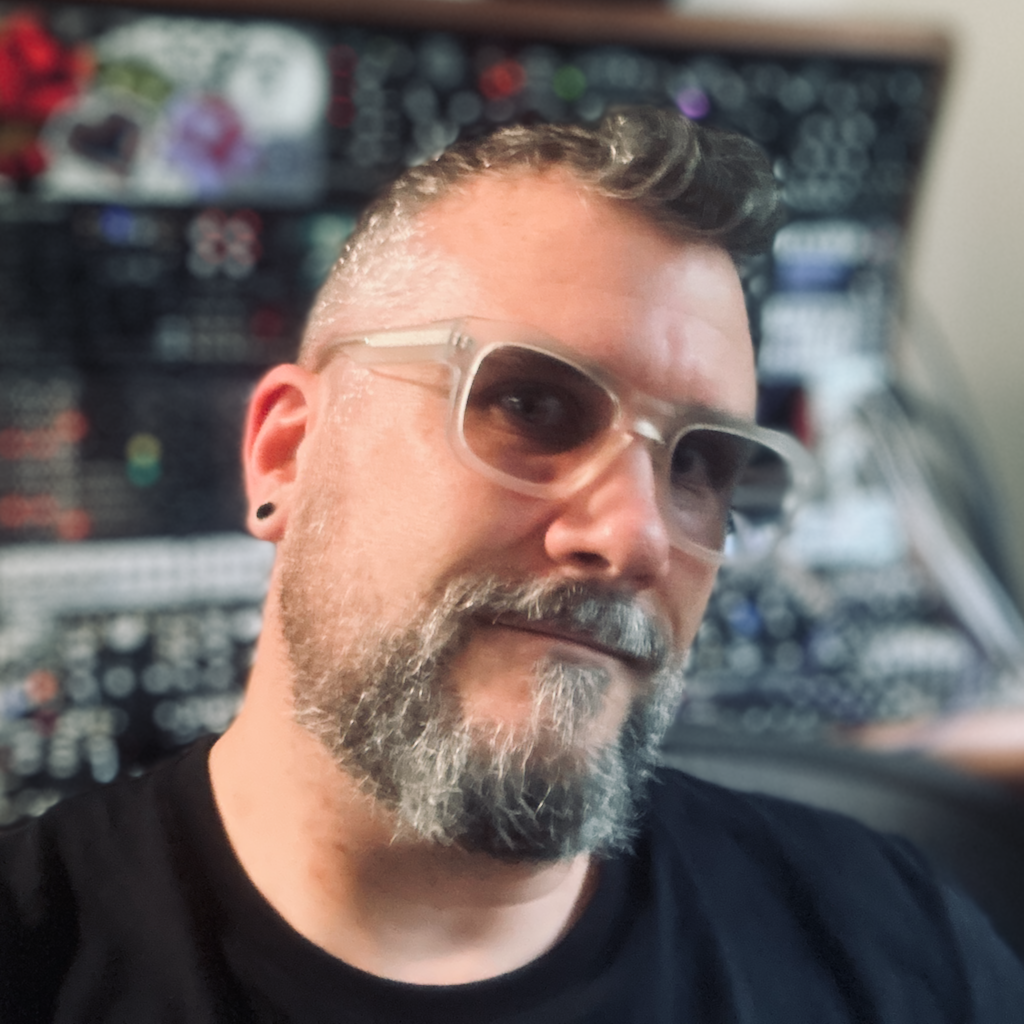 Dysonant, writer for knobulism, sitting in front of their modular synth in their home studio.